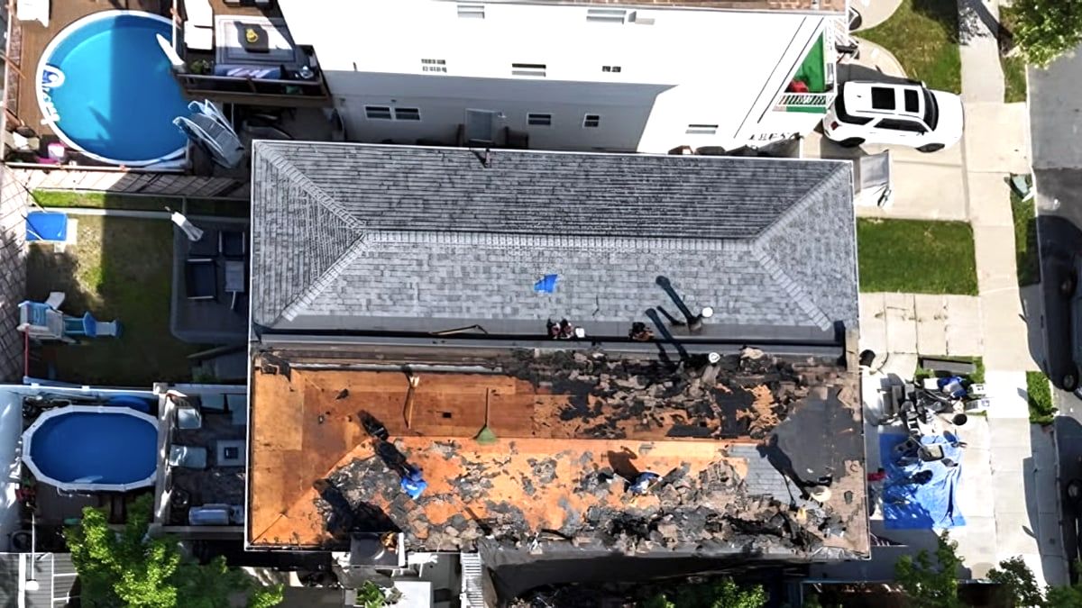 Aerial of roof tear-off, half new shingles, half exposed decking